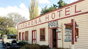 Un edificio histórico con la inscripción 'Cardrona Hotel' y un letrero que anuncia 'Gaelic Old Smuggle Whisky'.