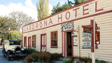 Un bâtiment historique portant l’inscription « Cardrona Hotel » et une enseigne indiquant « Gaelic Old Smuggle Whisky ».