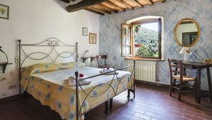Une chambre à coucher comprenant un lit, un bureau, une chaise, une fenêtre donnant sur un paysage agréable et un miroir.