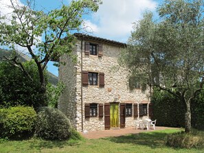 A stone building with a tiled roof, wooden shutters, and a small patio with outdoor furniture. - Girasole by Interhome (Lucca)