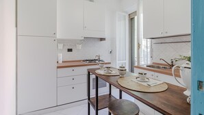 Una cucina compatta con mobili bianchi, un piano di lavoro in legno, un fornello a gas e un lavandino.