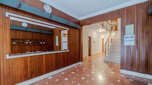 Un corridoio con rivestimenti in legno, una reception con uno specchio, una bacheca e una scala che conduce a un altro piano.