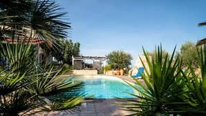 A swimming pool with a pergola and potted plants in a landscaped area.