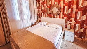 Habitación de hotel con cama, mesita de noche, un reloj de pared y un papel tapiz estampado.