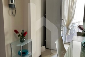 Ein modernes Hotelzimmer mit Glastrennwand, einer Vase mit roten Blumen und einer blauen Glasbowl auf einem Regal.