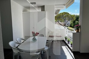 A balcony with a dining table and chairs, potted plants, and a view of a tree and buildings. - Homiday - Riviera D'Orazio (Giulianova)
