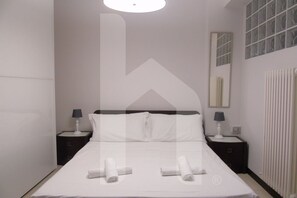 A hotel room with a large bed, two bedside tables with lamps, a mirror, and a radiator. - Homiday - Riviera D'Orazio (Giulianova)
