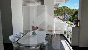 A balcony with a dining table and chairs, potted plants, and a view of a tree and buildings. - Homiday - Riviera D'Orazio (Giulianova)