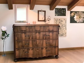 Ein hölzerner Kommode mit Schubladen, ein Spiegel und Kunstwerke an der Wand.
