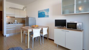 Una cocina compacta con zona de comedor, microondas y un cuadro en la pared.