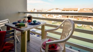 Un balcón con una mesa, sillas y vistas a un puerto deportivo con barcos.