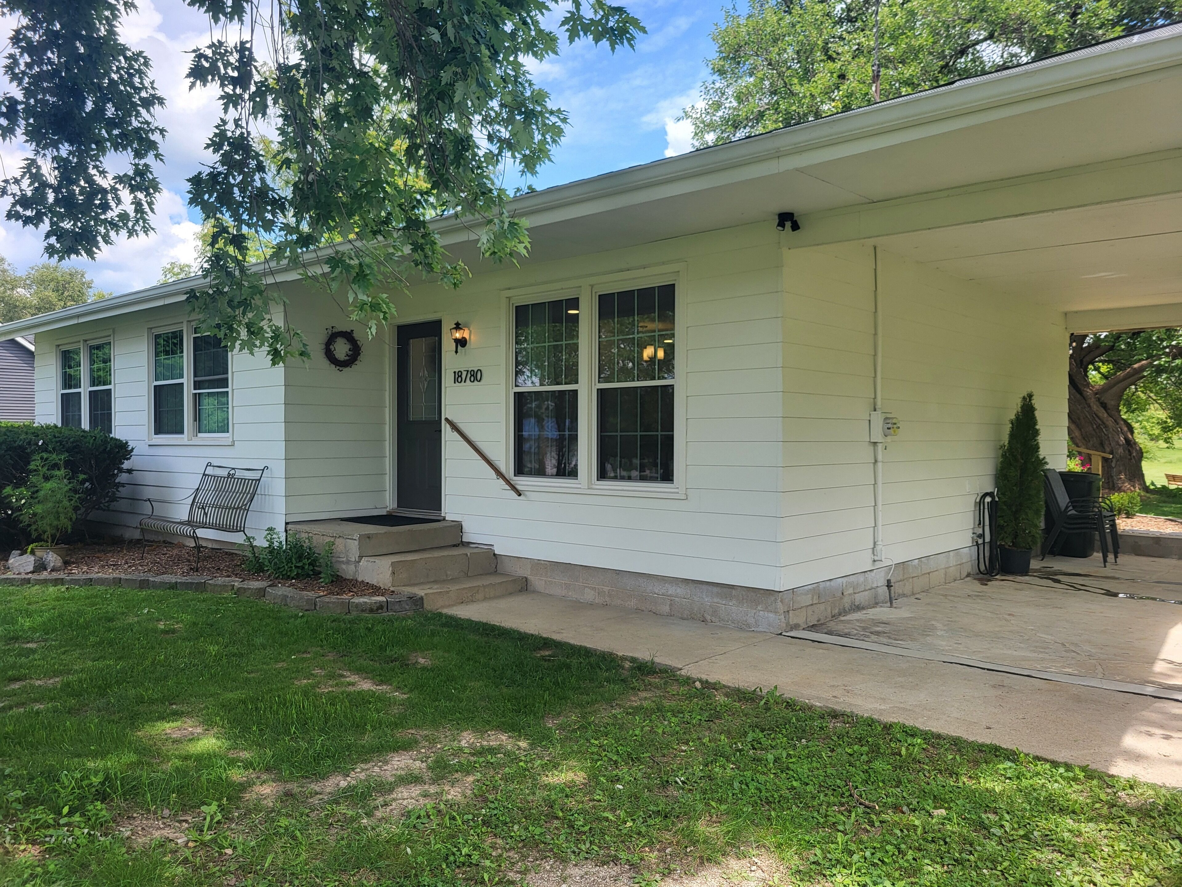 A single-story house with a front porch, a mailbox, and a number '18780' on the door.