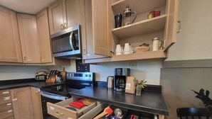 A modern kitchen with wooden cabinets, a stainless steel microwave, a coffee maker, and a drawer organizer.