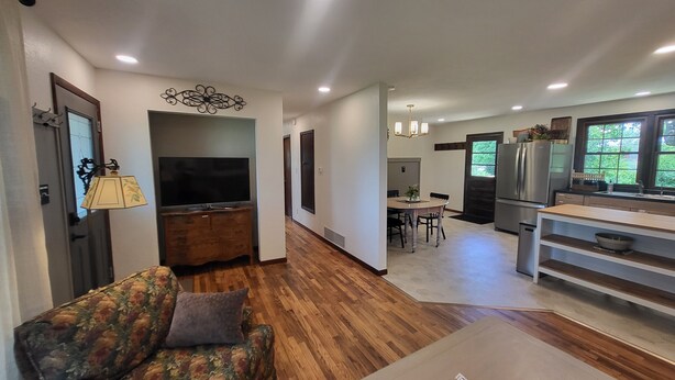 A modern living room with a sofa, a television, and a dining area with a table and chairs.