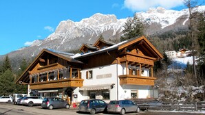 Un edificio de madera con balcones, un letrero de restaurante y montañas al fondo.