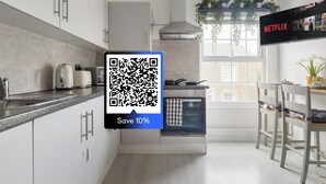 Une cuisine moderne avec des meubles blancs, un four encastré et un coin repas comprenant une table et des chaises.