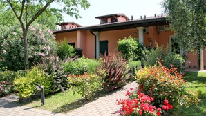 A building with a garden pathway leading to a door with a green shutter.