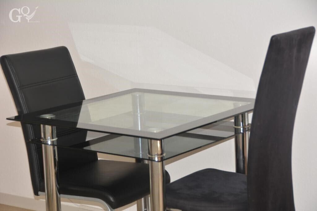 Zona pranzo moderna con tavolo in vetro e sedie rivestite in tessuto nero.