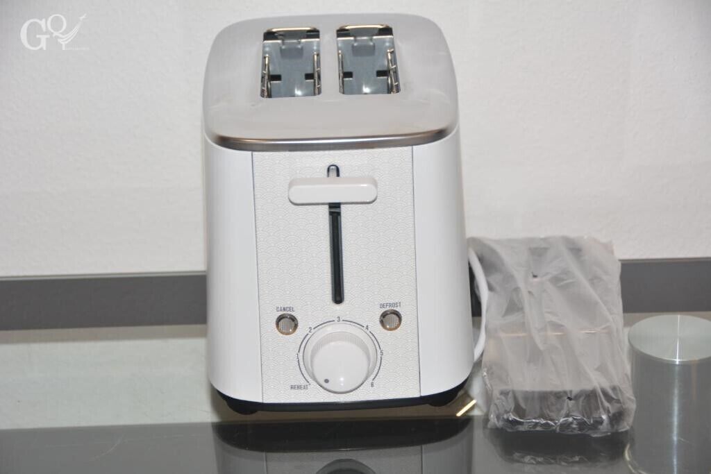 Un grille-pain blanc à deux fentes, un panneau de commande avec un bouton rotatif et des boutons, et un sac en plastique à côté.
