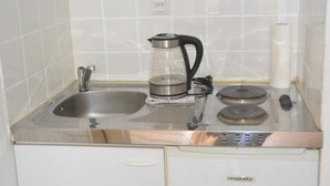 Ett kök med en diskho i rostfritt stål, en kaffebryggare, en vattenkokare och en rulle hushållspapper.