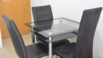 Un comedor moderno con una mesa de vidrio y cuatro sillas negras.
