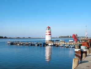 A lighthouse at a dock with several boats moored nearby.