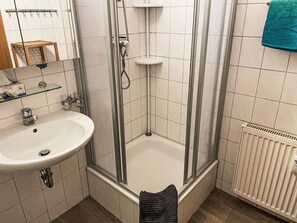 Ein Badezimmer mit Dusche, Waschbecken und Handtuchhalter.