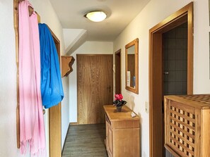 A hallway with wooden doors, a wooden bench, and a mirror on the wall. - Boddenbrise by Interhome (Waase)
