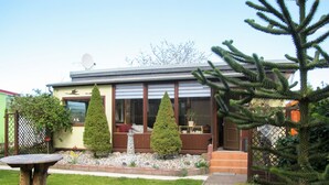 A modern house with a patio, two potted evergreen trees, and a satellite dish. - Vacation home Karli by Interhome (Loissin)