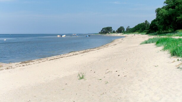 A beach with a sandy shore, calm water, and boats. - Vacation home Karli by Interhome (Loissin)