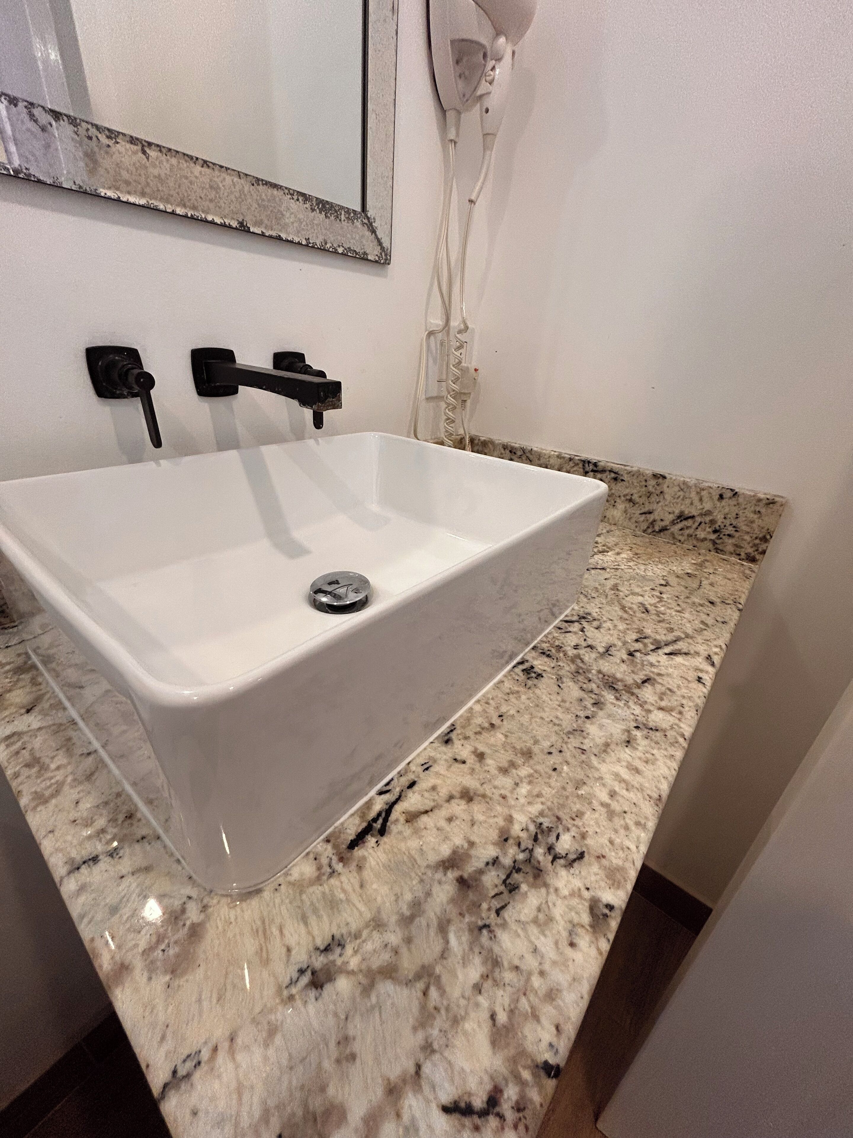 A bathroom with a white sink, a mirror, and a granite countertop.