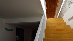 Una escalera de madera con barandillas blancas que lleva a una zona de recepción.