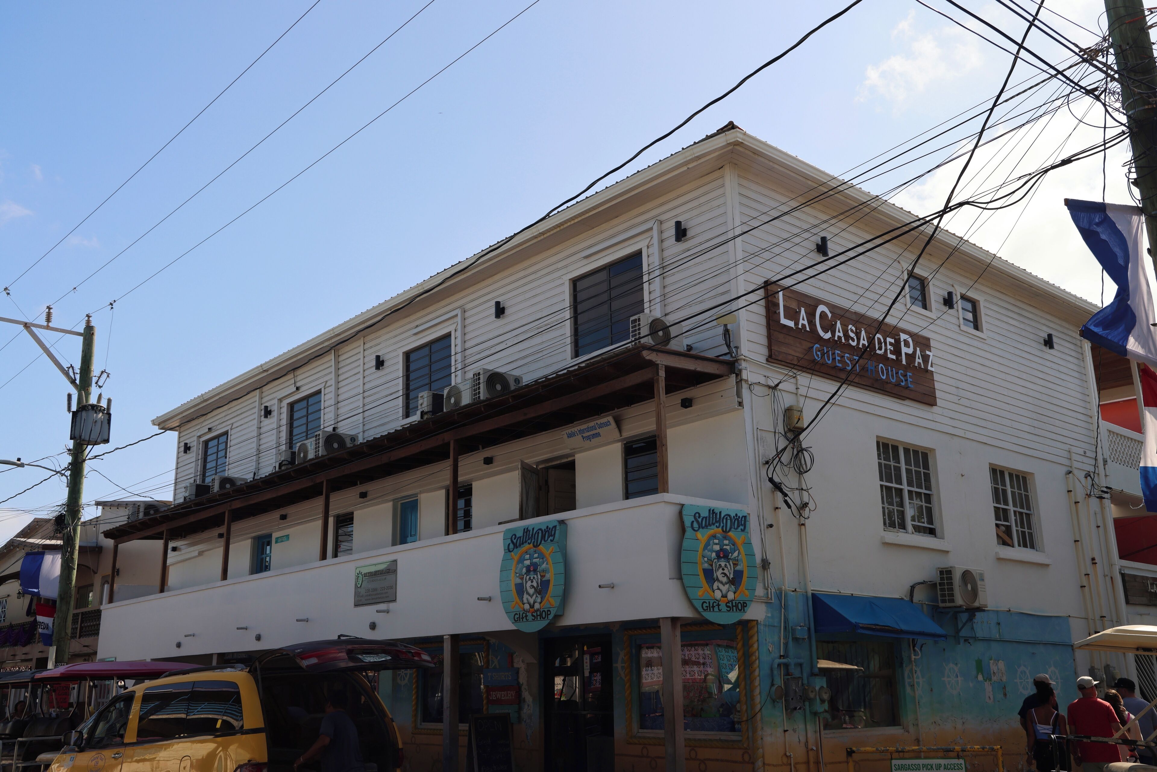 Un edificio de dos pisos con un letrero que indica 'La Casa de Paz Guest House' y 'Sally's Gift Shop' en la planta baja.
