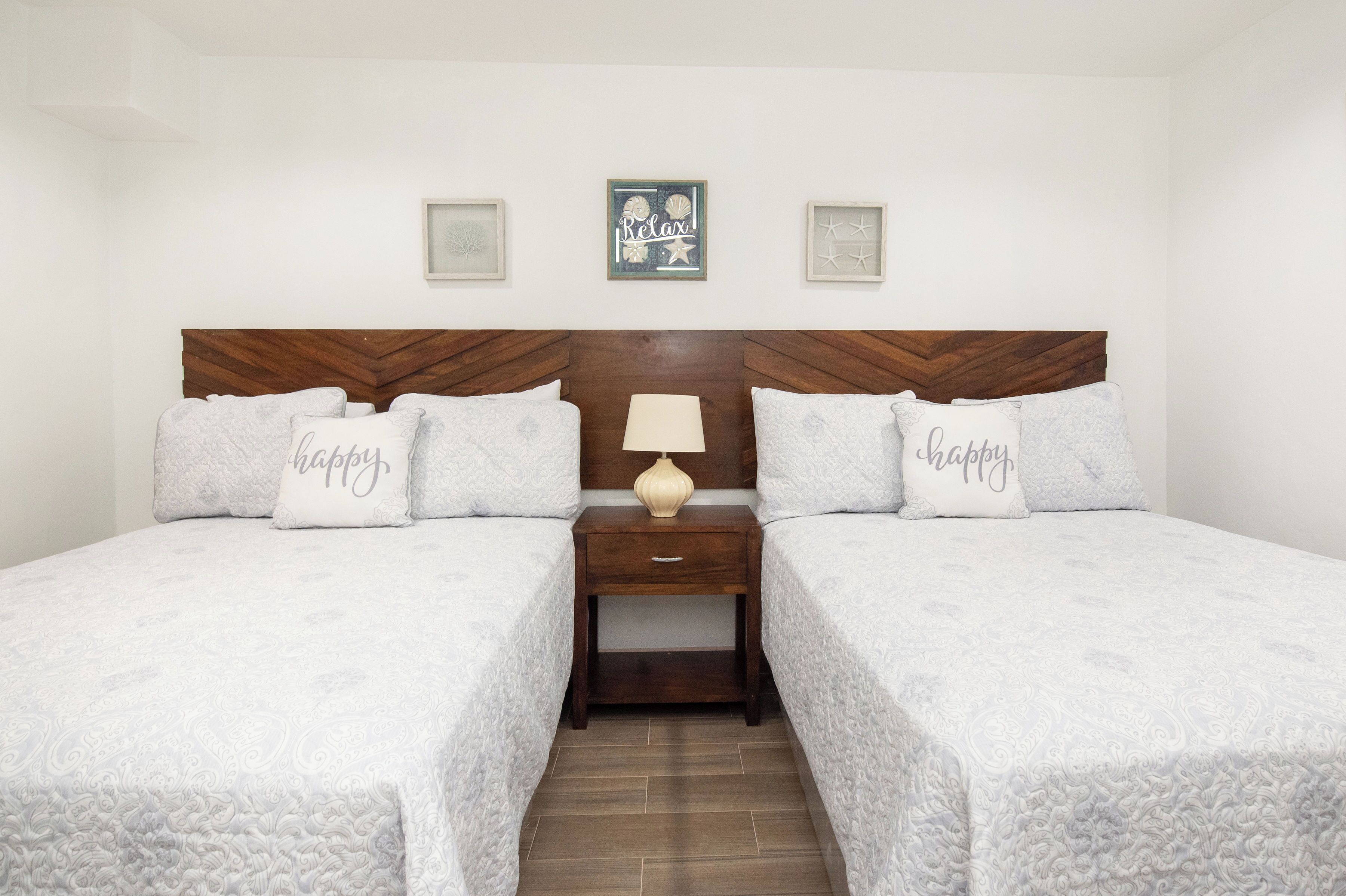 A double bed with two pillows, a bedside table, and a wall-mounted picture.