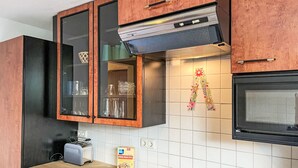 A kitchen with wooden cabinets, a built-in microwave, and a toaster. There are bananas and a box of cereal on the counter.