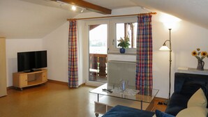 Een woonkamer met een blauwe bank, een televisie op een houten kast, een glazen salontafel en een lamp.