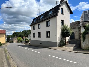 Une maison à deux étages, avec un toit en pente, de nombreuses fenêtres et le numéro « 17 » bien visible sur la façade.