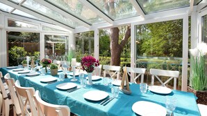 A conservatory with a table set for a meal, surrounded by chairs and glassware. - Deichhaus Küstenwind by Interhome (Fedderwardersiel)