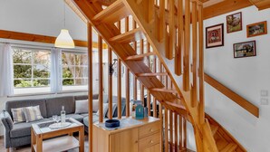 En modern inredning med en trätrappa, en soffa, ett soffbord och en matplats.