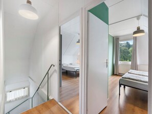 A modern bedroom with a bed, a window with curtains, and a staircase with a glass railing. - Lužnice by Interhome (Tyn nad Vltavou)