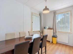 A dining area with a wooden table, four chairs, a microwave on a cabinet, and a trash bin. - Lužnice by Interhome (Tyn nad Vltavou)