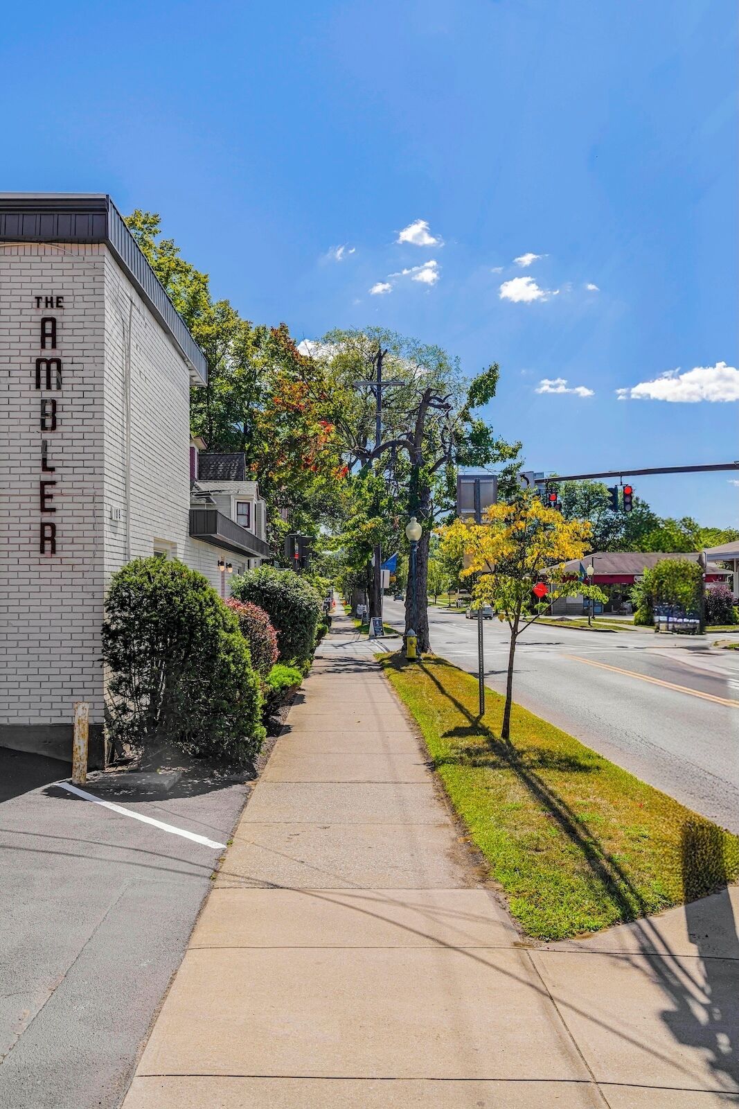 A sidewalk adjacent to a building with a sign reading "THE AMBER".