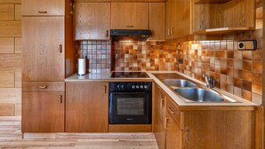 Una cocina con armarios de madera, estufa negra, fregadero y salpicadero de azulejos.