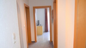 Un couloir doté d’un revêtement de sol en moquette et de portes en bois qui donnent sur une pièce contenant un bureau et un ordinateur.