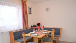 Un espace repas avec une table en bois, dressée pour quatre personnes, entourée de bancs rembourrés.