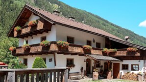 Ein traditionelles Chalet mit Holzbalkonen und Blumenkästen vor einer Bergkulisse.