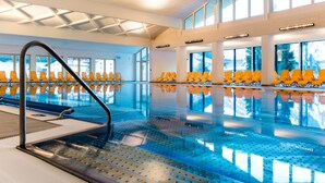 Una piscina interior con sillas amarillas y una vista despejada del exterior a través de amplios ventanales.