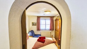 Un dormitorio con cama, ventana con cortinas, radiador y armario.