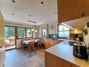 Eine moderne Küche mit Essbereich, großen Fenstern und Blick ins Freie.