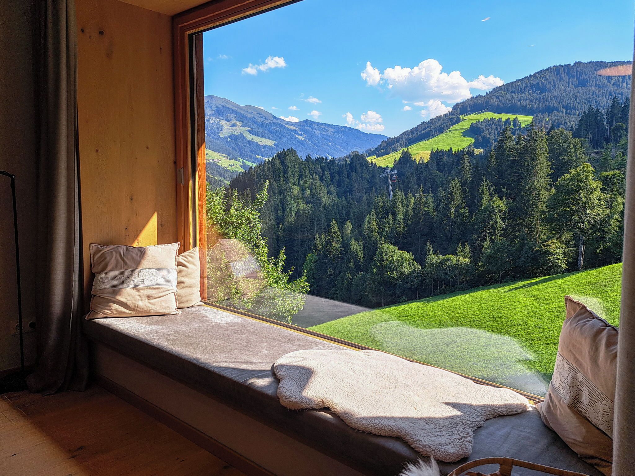 Een kamer met een groot raam met uitzicht op een bergachtig landschap.